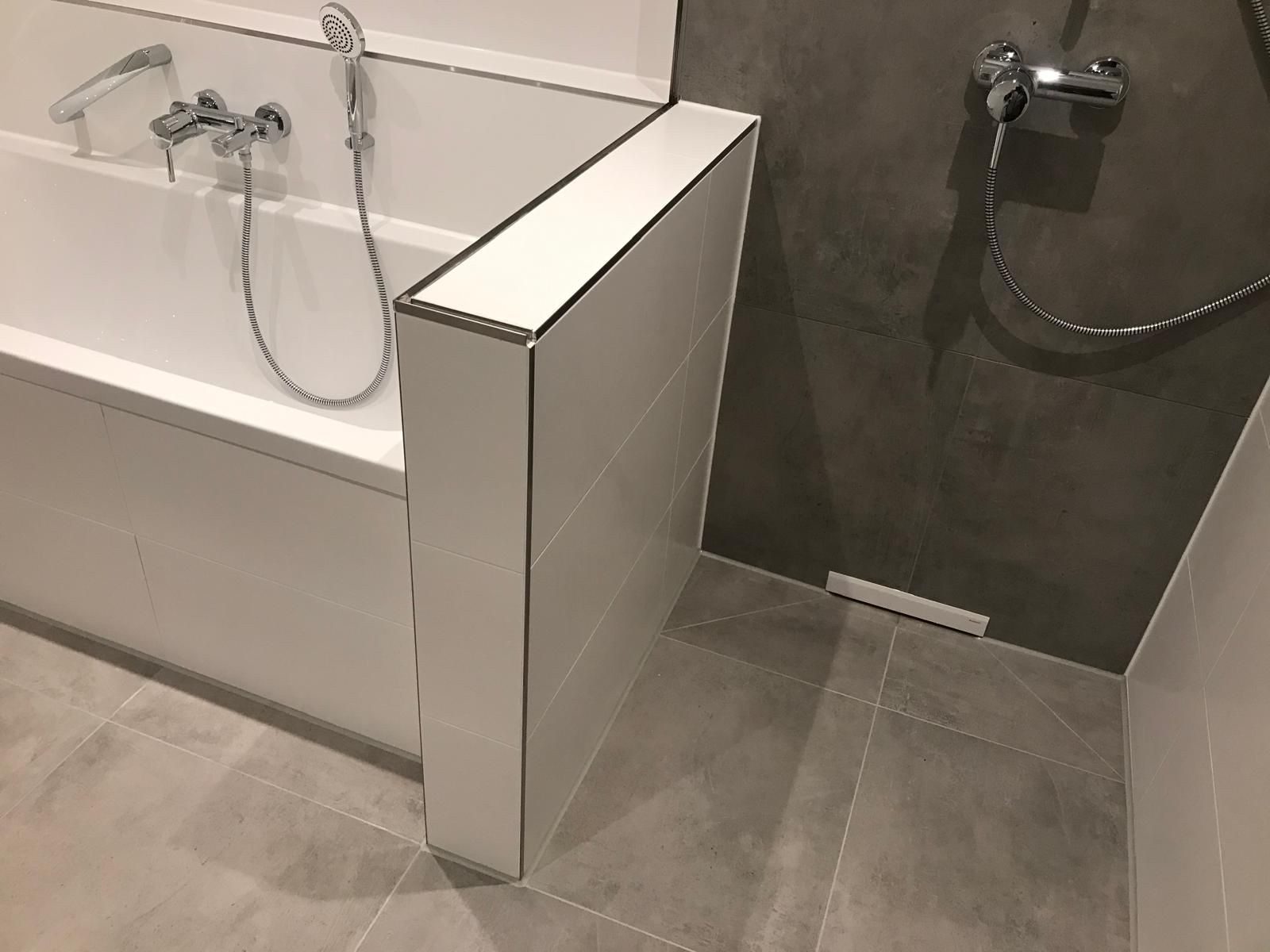 Graue Großformatfliesen in Betonoptik mit bodengleicher Dusche neben der Badewanne